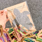 Skaidrioje plastikinėje pakuotėje supakuotas siuvinėjimo edukacinis rinkinys „Vėžliukas“ su siūlais, adata ir instrukcija